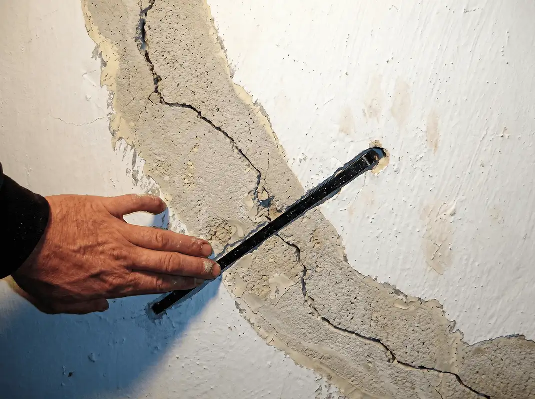A wall with a large crack is being inspected by a professional in Albuquerque, NM