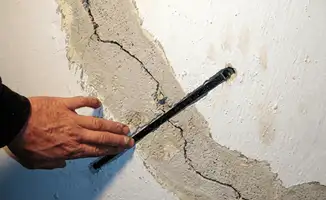 A wall with a large crack is being inspected by a professional in Albuquerque, NM